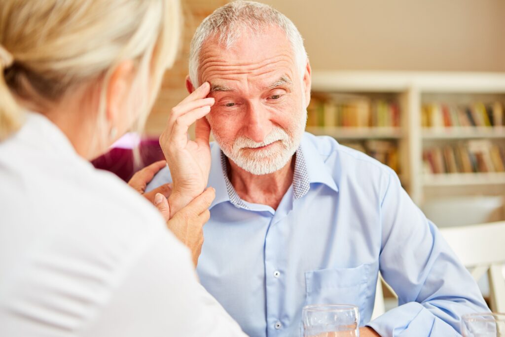 A caregiver consoles a frustrated older adult about their dementia during a healthcare checkup